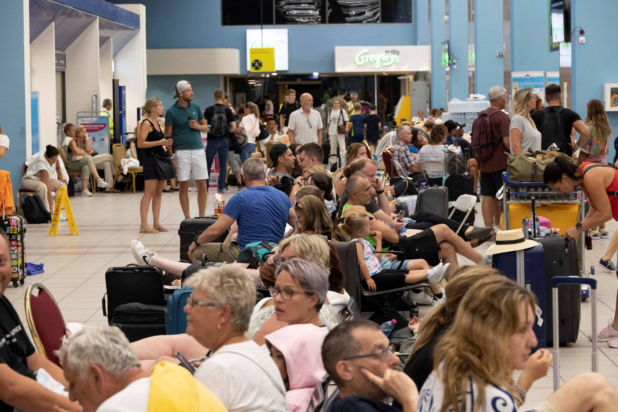 tourists wait for departing planes at the airport, after being evacuated following a wildfire in rhodes